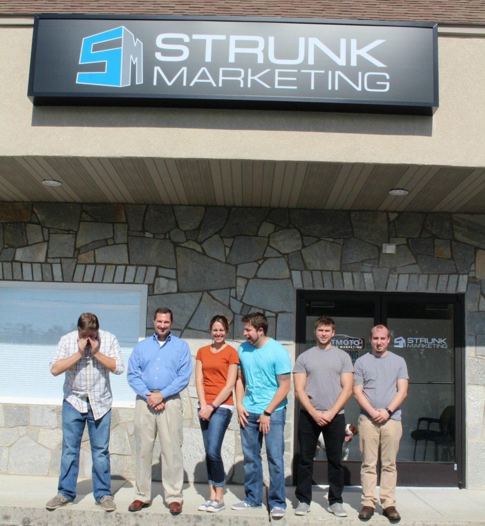 5 men and 1 woman standing out front of Strunk Media Group.