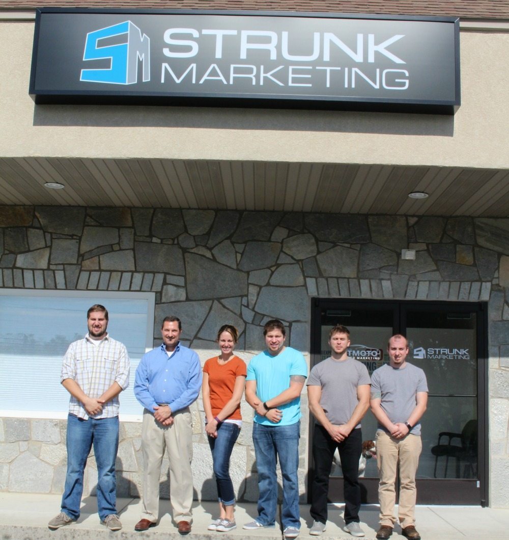 A picture of 5 men and 1 woman outside of Strunk Media Group's website.